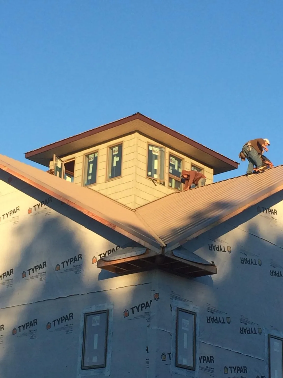 Roofers working around a rooftop cupola on a new metal roof at sunset — Roof Waterproofing in Mayville by Roofing Brothers